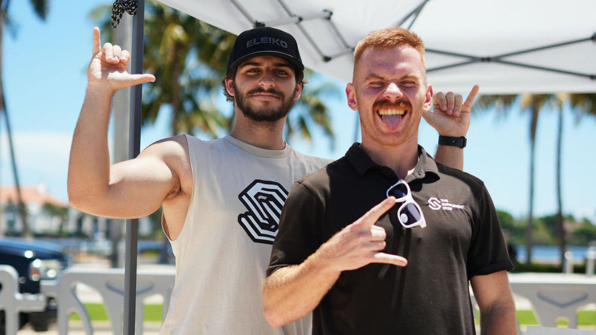 Two men posing for a photo as representatives of The Supplement Stop—smiling and wearing branded apparel, representing the company at an event.